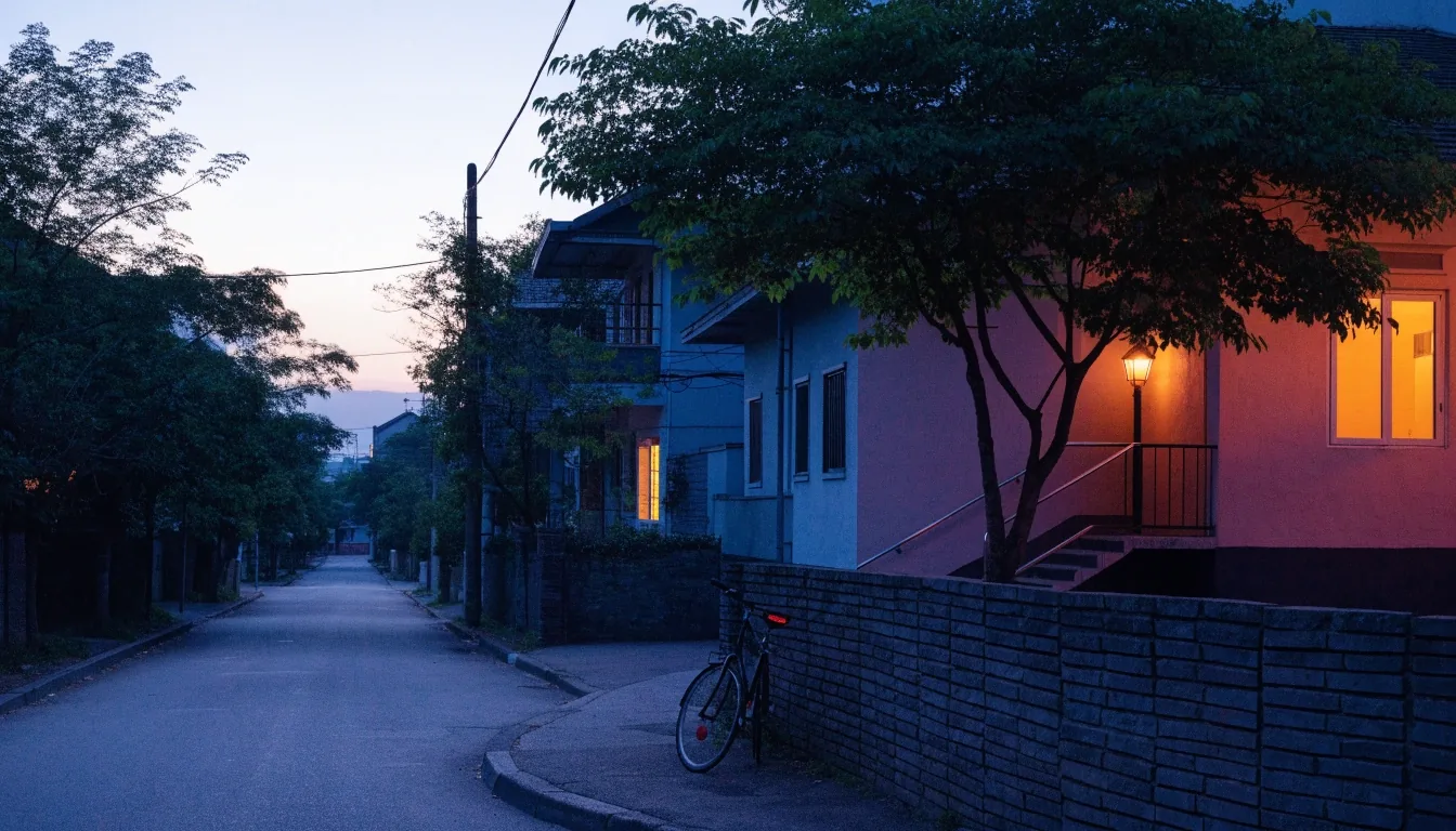 Quiet Jakarta residential street at evening with warm lit windows and leafy trees